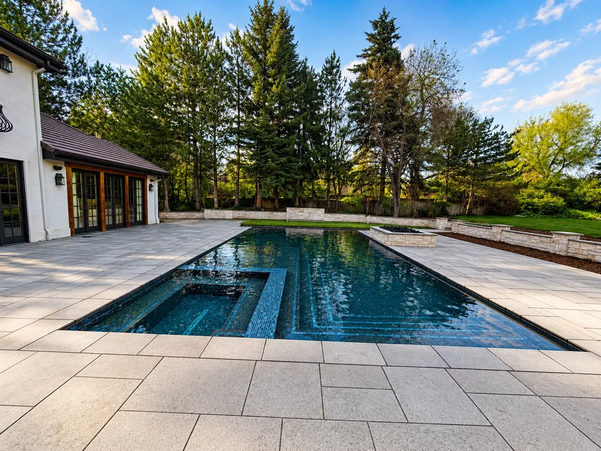 Glass-tiled pool with an in-water bench and large-format stone decking